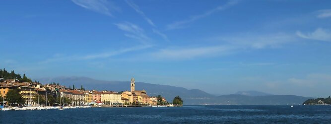 Kurzurlaub beliebte Urlaubsziele am Gardasee -  Mit einer Fläche von 370 km² ist der Gardasee der größte See Italiens. Es liegt am Fuße der Alpen und erstreckt sich über drei Staaten: Lombardei, Venetien und Trentino. Die maximale Tiefe des Sees beträgt 346 m, er hat eine längliche Form und sein nördliches Ende ist sehr schmal. Dort ist der See von den Bergen der Gruppo di Baldo umgeben. Du trittst aus deinem gemütlichen Hotelzimmer und es begrüßt dich die warme italienische Sonne. Du blickst auf den atemberaubenden Gardasee, der in zahlreichen Blautönen schimmert - von tiefem Dunkelblau bis zu funkelndem Türkis. Majestätische Berge umgeben dich, während die Brise sanft deine Haut streichelt und der Duft von blühenden Zitronenbäumen deine Nase kitzelt. Du schlenderst die malerischen, engen Gassen entlang, vorbei an farbenfrohen, blumengeschmückten Häusern. Vereinzelt unterbricht das fröhliche Lachen der Einheimischen die friedvolle Stille. Du fühlst dich wie in einem Traum, der nicht enden will. Jeder Schritt führt dich zu neuen Entdeckungen und Abenteuern. Du probierst die köstliche italienische Küche mit ihren frischen Zutaten und verführerischen Aromen. Die Sonne geht langsam unter und taucht den Himmel in ein leuchtendes Orange-rot - ein spektakulärer Anblick.